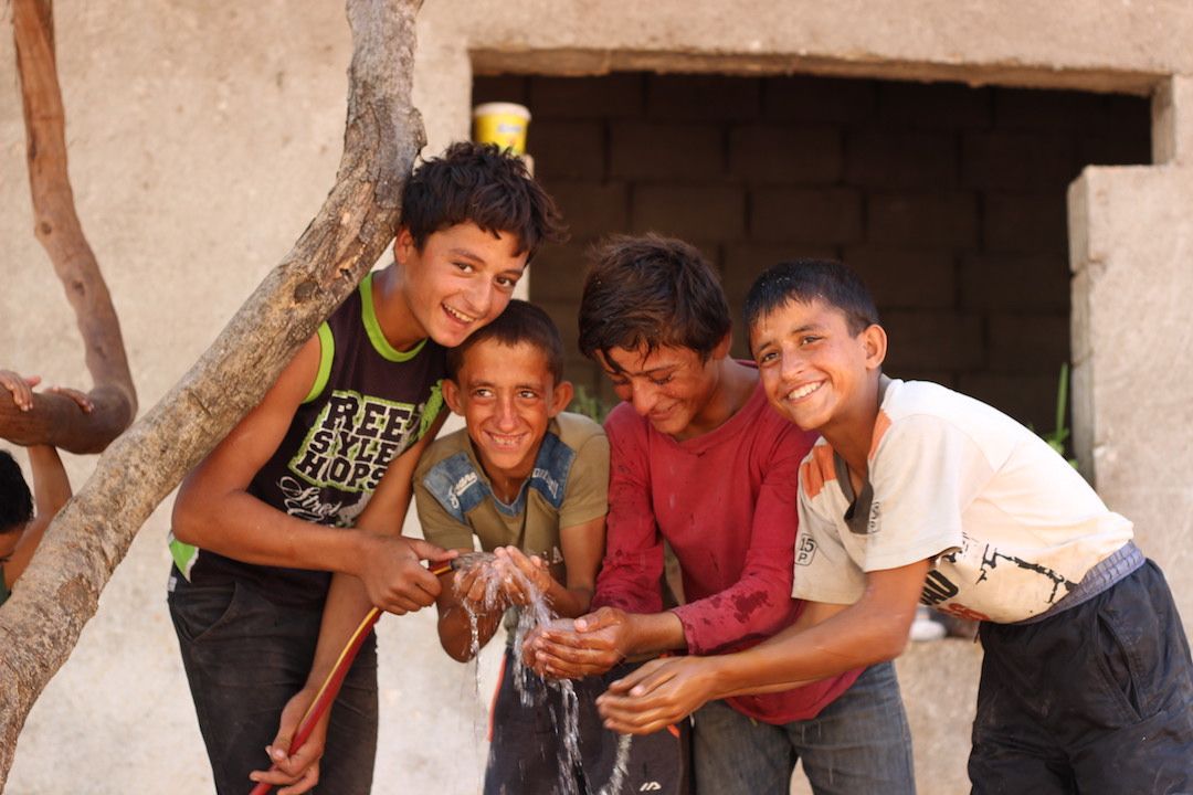 khalid obeid alabdullah-12 years old--ahmed steif alabdullah 12 years--muhammed mraie alabdullah 10- hashem marie alabdullah 8 Syrian children play with a water hose, provided and supported by GOAL in September 2018. WASH